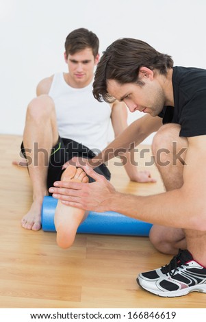 Physical therapist examining a young mans leg at the hospital gym
