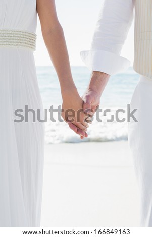 Newlyweds holding hands close up at the beach