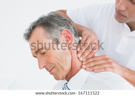 Close-up of a male chiropractor massaging patients neck over white background