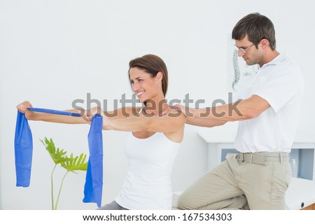 Male therapist assisting young woman with exercises in the medical office
