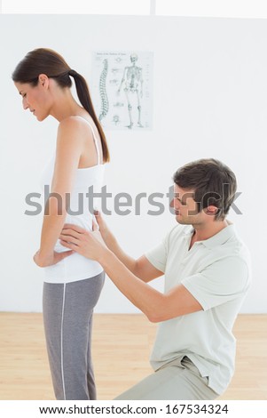 Side view of a male physiotherapist examining woman\'s back in the medical office