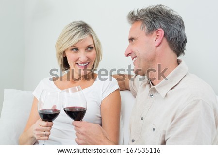 Relaxed happy couple toasting wine glasses at home