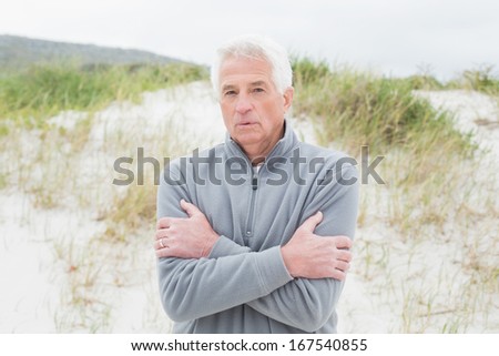 Portrait of a casual senior man feeling cold at the beach
