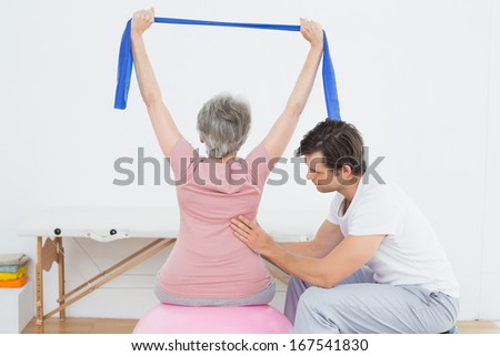 Senior woman sitting on yoga ball while working with a physical therapist