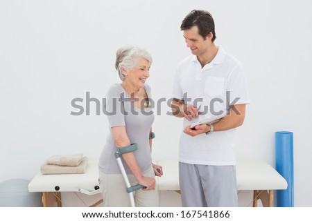 Male therapist discussing reports with a disabled senior patient in the gym at hospital
