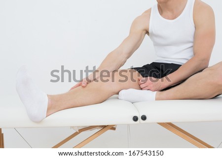 Low section of a young man sitting on examination table in the medical office