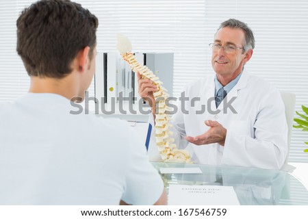 Male doctor explaining the spine to a patient in medical office