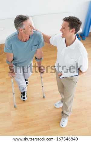High angle view of a male therapist and disabled patient with reports in the gym at hospital