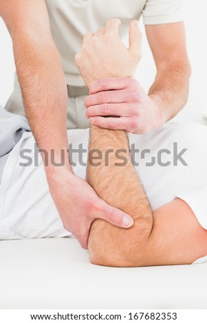 Mid section of a male physiotherapist examining a young man\'s hand in the medical office