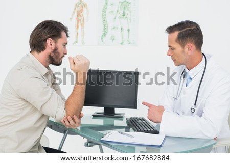 Male doctor in conversation with patient at desk in medical office