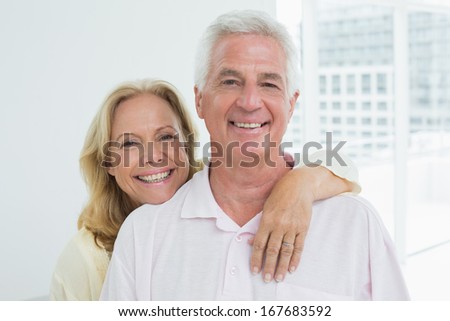 Portrait of a happy senior woman embracing man from behind at home