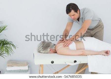 Male physiotherapist massaging a senior woman\'s back in the medical office