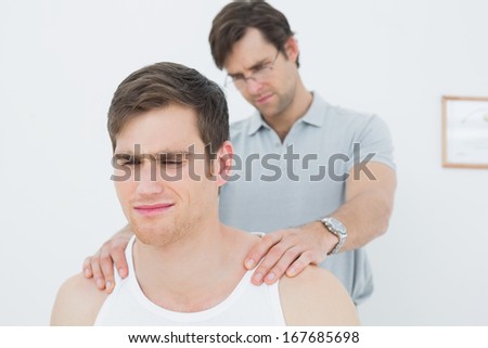 Male physiotherapist massaging a young mans shoulder in the medical office