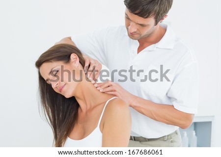 Male chiropractor massaging a young woman\'s neck in the medical office