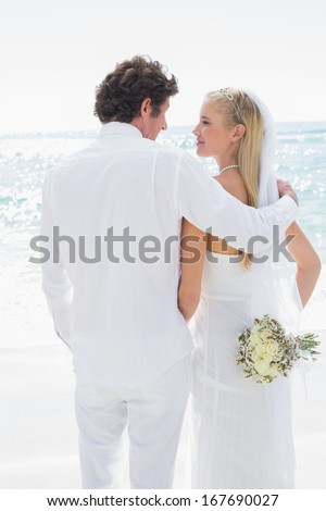 Happy bride and groom looking at each other at the beach