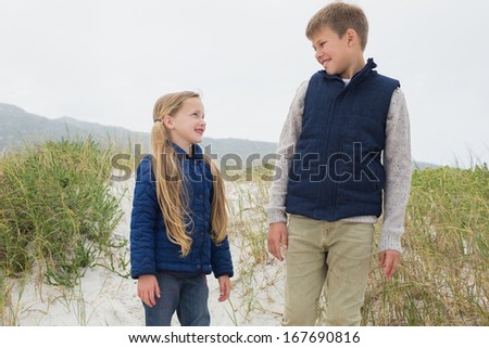 Low angle view of a happy brother and sister standing at the beach