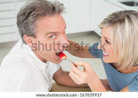 Close-up of a loving woman feeding man in the kitchen at home