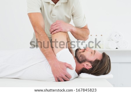 Male physiotherapist stretching a young man\'s hand in the medical office