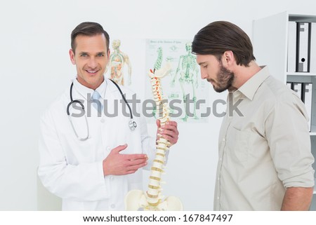 Portrait of a male doctor explaining the spine to a patient in medical office
