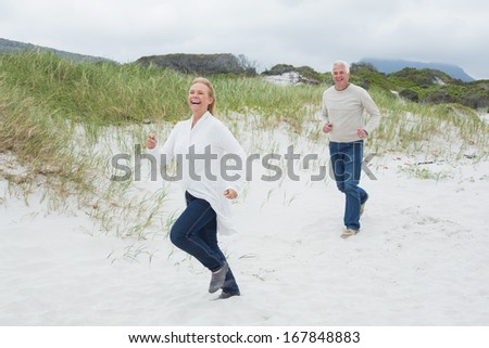 Full length of a cheerful senior couple running at the beach