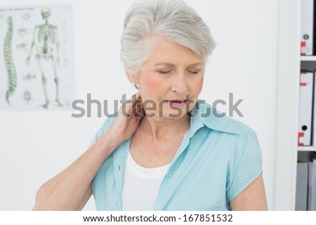 Senior woman suffering from neck pain with eyes closed in the medical office