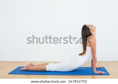 Full length of a fit young woman doing the cobra pose in fitness studio