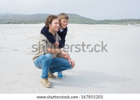 Full length side view of a casual man and son relaxing at the beach