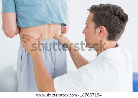 Close-up of hands massaging mans lower back in the gym at hospital