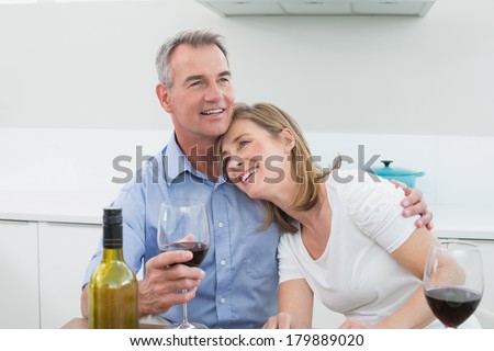 Loving couple with wine glasses in the kitchen at home