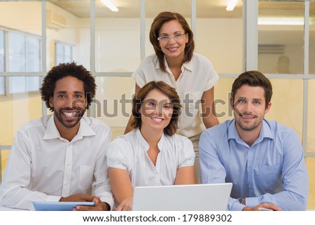 Portrait of smiling young business people using laptop together at office