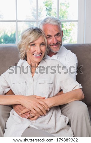 Portrait of a mature man embracing woman from behind in the living room at home