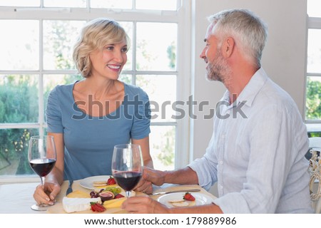 Portrait of a happy mature couple with wine glasses having food at home