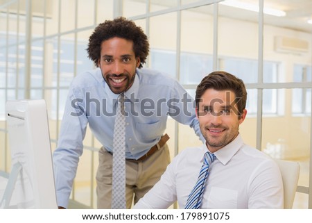 Portrait of two smiling young businessmen with computer in the office