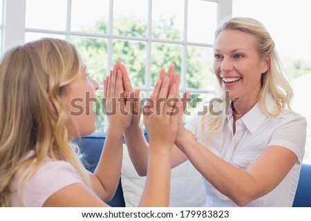 Happy mother playing clapping game with daughter in house