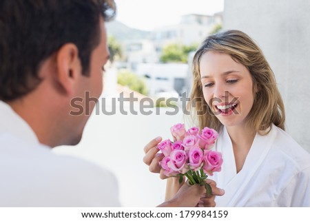 Close-up of a man giving happy woman flowers at home