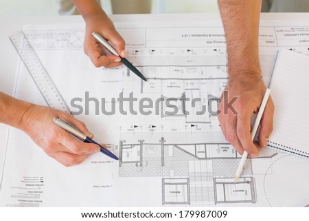 Extreme close-up of several hands working on blueprints in the office
