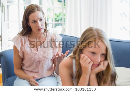 Unhappy girl not talking after an argument with mother in the living room at home