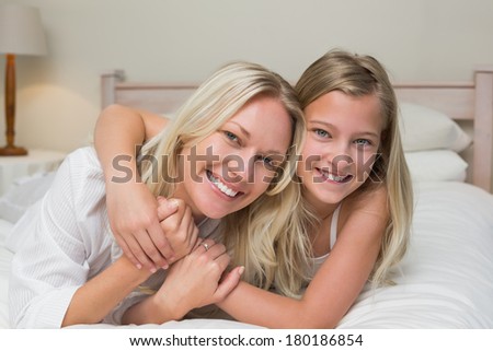 Portrait of loving mother and daughter lying in bed at home