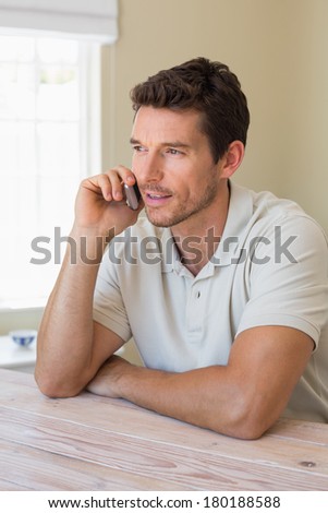 Smiling young man using mobile phone at home