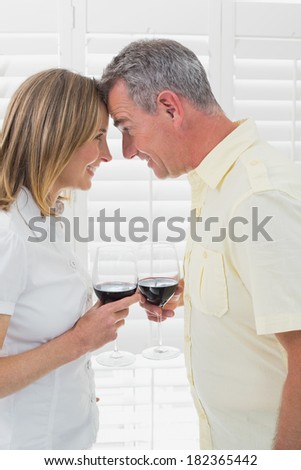 Side view of a happy couple toasting wine glasses at home