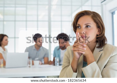 Close-up of a serious businesswoman with colleagues in meeting in background at the office