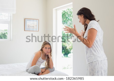 Young angry mother scolding daughter in bedroom