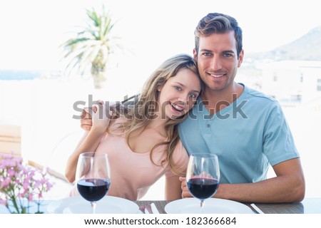 Portrait of a loving young couple with wine glasses sitting at dining table