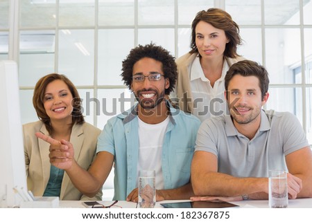 Group portrait of young business people with computer sitting at office desk