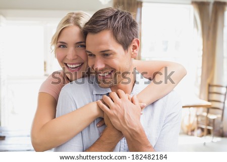 Close-up portrait of a happy young woman embracing man from behind at home