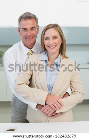Happy businessman embracing woman from behind in the kitchen at home