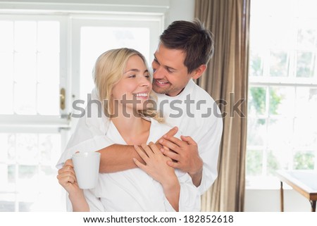 Portrait of a loving young man embracing woman from behind at home
