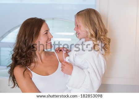 Smiling mother and daughter with toothbrush in the bathroom at home