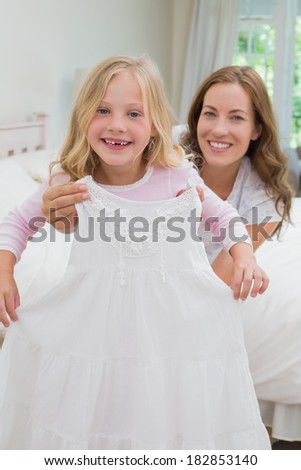 Portrait of a mother trying new dress for her happy daughter at home