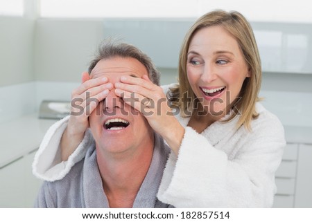 Close-up of a happy woman covering man\'s eyes in the kitchen at home